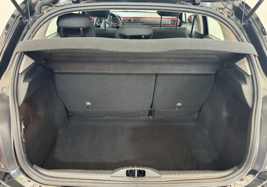 Coffre ouvert d'une Citroën C3 noire vue de l'arrière, montrant l'espace de chargement et la tablette cache-bagages relevée.