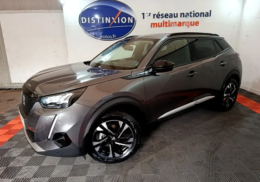 Peugeot 2008 gris foncé vue 3/4 avant droit, avec jantes noires et toit noir dans un showroom intérieur.