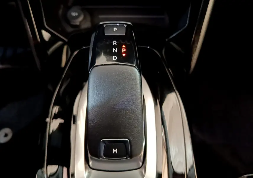 Le levier de vitesses automatique noir du Peugeot 2008 PureTech 130 vu de dessus dans un intérieur sombre.