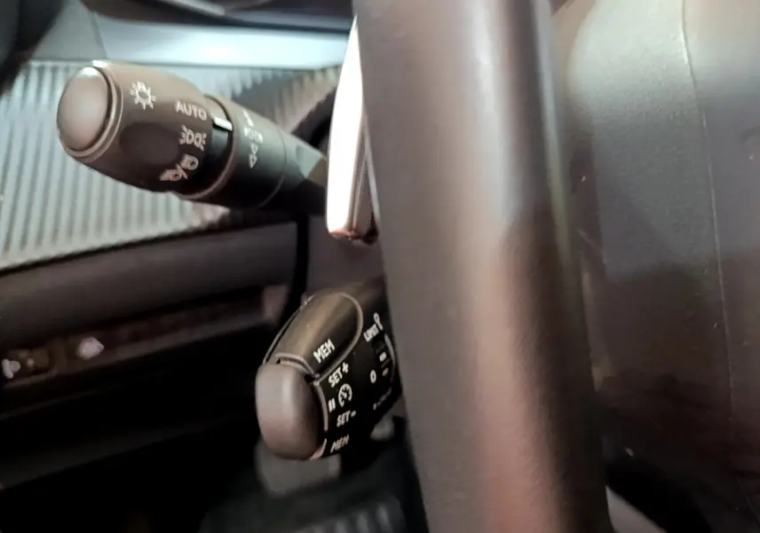 Gros plan sur la commande de régulateur de vitesse et le commodo d’éclairage, intérieur noir du Peugeot 2008 gris foncé.