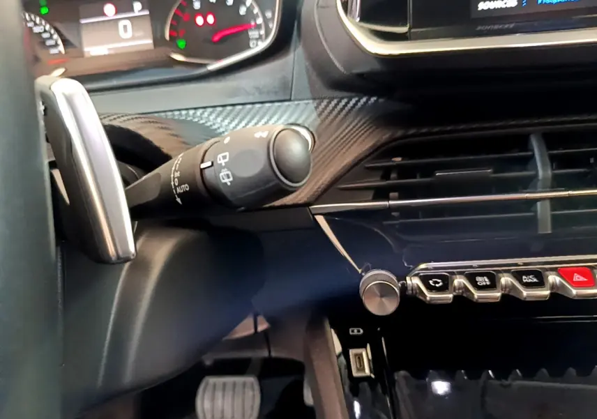 Gros plan intérieur sur le tableau de bord et commandes du Peugeot 2008 gris foncé, avec volant et écran tactile visibles.