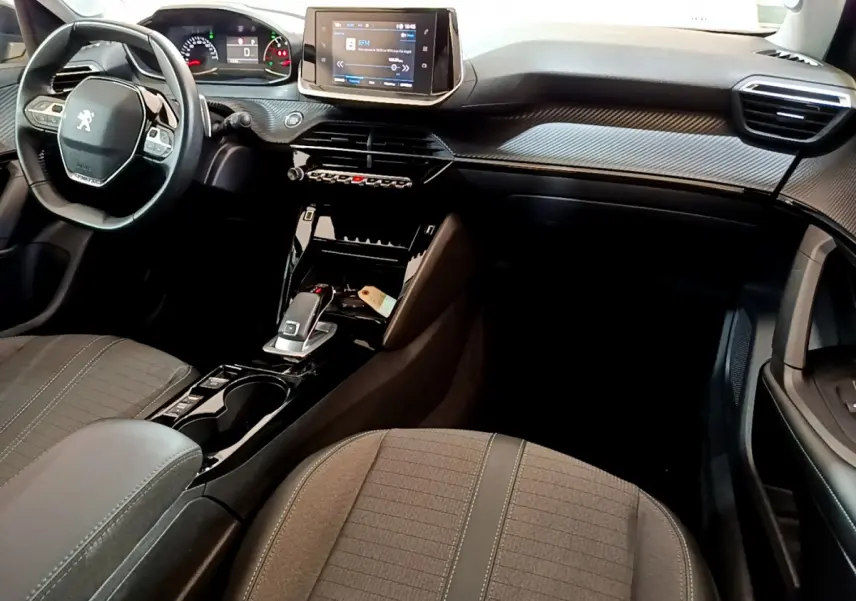 Vue intérieure côté conducteur de la Peugeot 2008 2022, tableau de bord noir avec écran tactile et volant compact cuir.