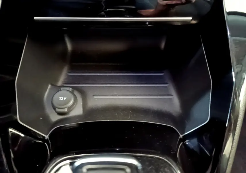 Gros plan sur la prise 12V dans le rangement central noir brillant de la Peugeot 2008 gris foncé, version Allure 2022.