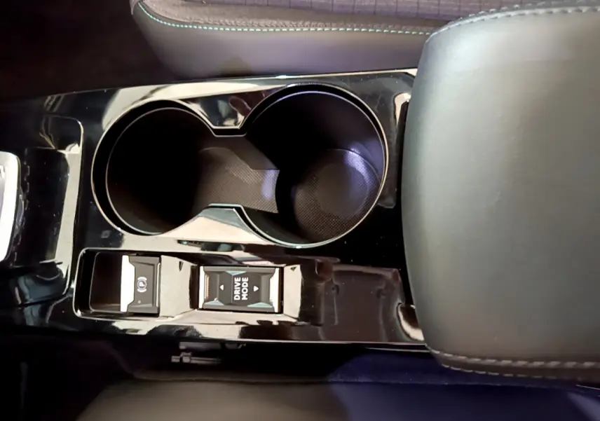 Vue rapprochée de la console centrale noire brillante du Peugeot 2008 avec porte-gobelets et commandes Drive Mode.