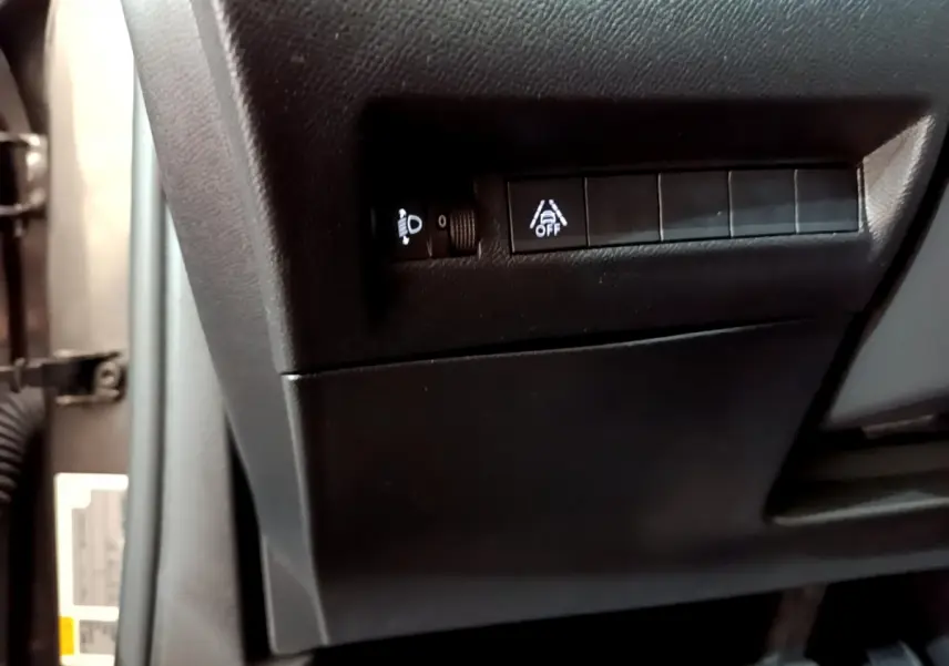 Gros plan sur les commandes de réglage des phares et d'alerte de franchissement de ligne à gauche du volant du Peugeot 2008 gris foncé.