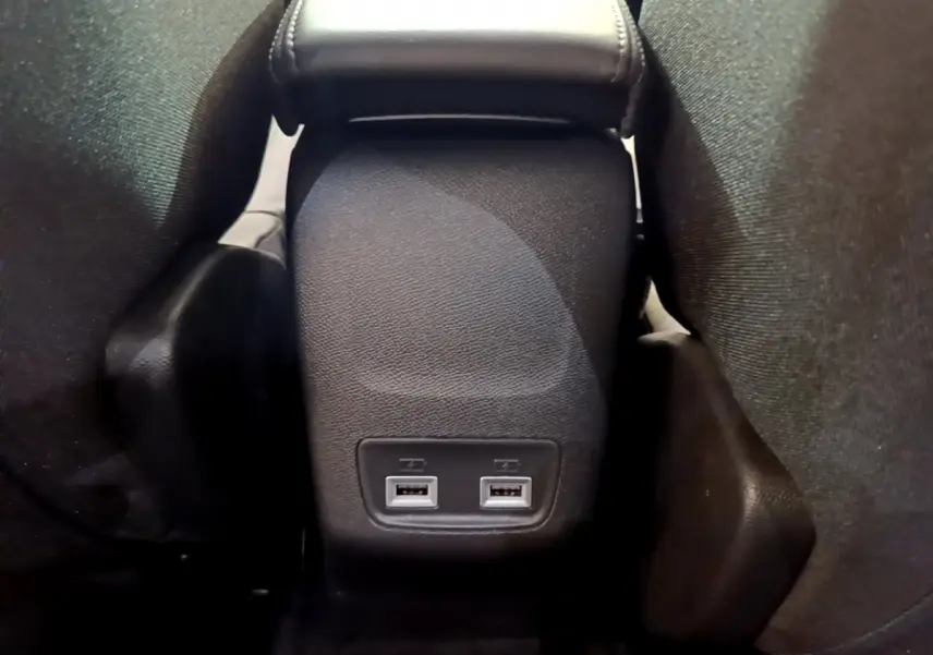 Vue rapprochée de la console centrale arrière noire du Peugeot 2008 avec deux ports USB visibles entre les sièges.