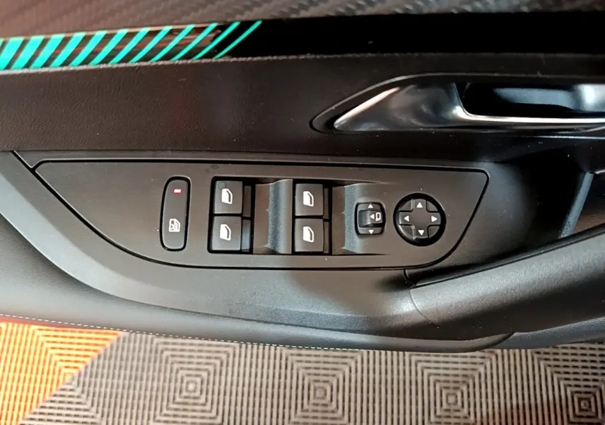 Vue rapprochée des commandes de lève-vitres et réglages des rétroviseurs sur la porte côté conducteur d’une Peugeot 2008 gris foncé.