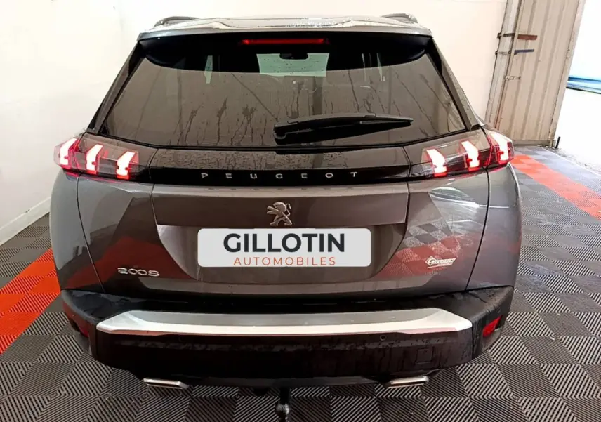 Vue arrière d’un Peugeot 2008 gris foncé avec feux LED allumés et attelage visible en intérieur d’exposition.