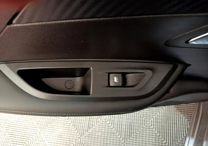 Gros plan sur la commande d’ouverture de trappe à carburant noire dans l’habitacle du Peugeot 2008 gris foncé.