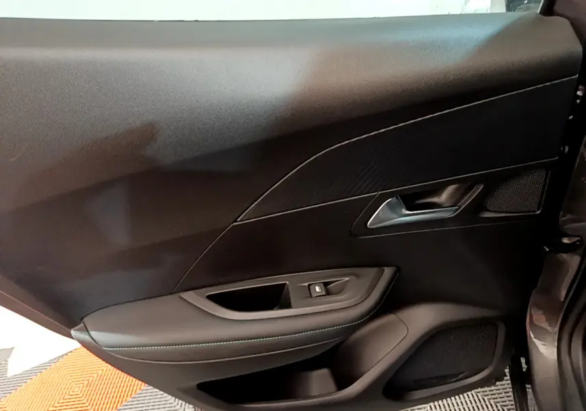 Vue intérieure côté gauche de la porte avant d'une Peugeot 2008 gris foncé avec garniture noire et poignée argentée.