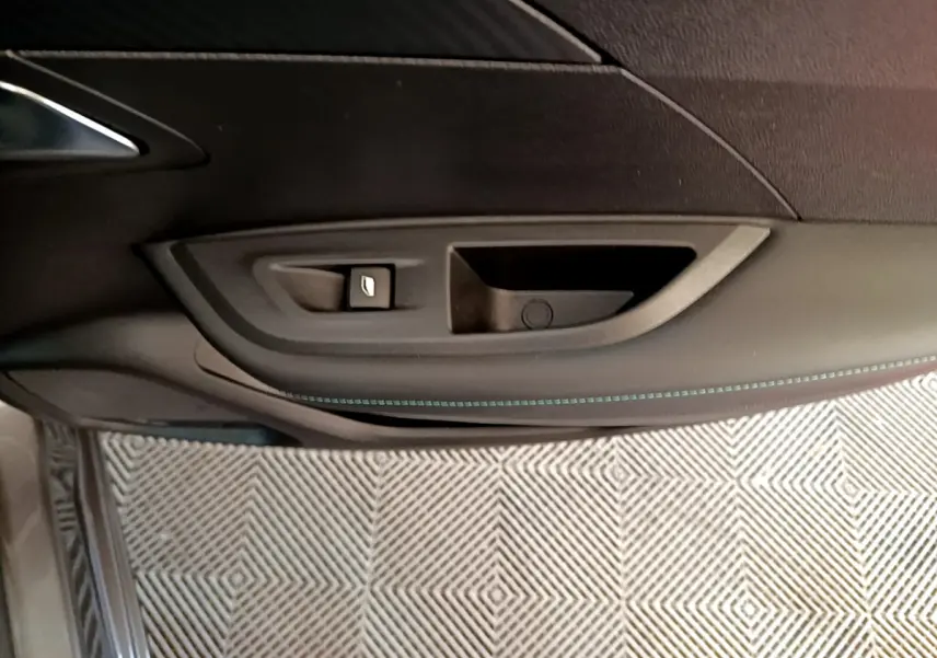 Gros plan sur la poignée intérieure et le bouton de lève-vitre côté conducteur du Peugeot 2008 gris foncé.