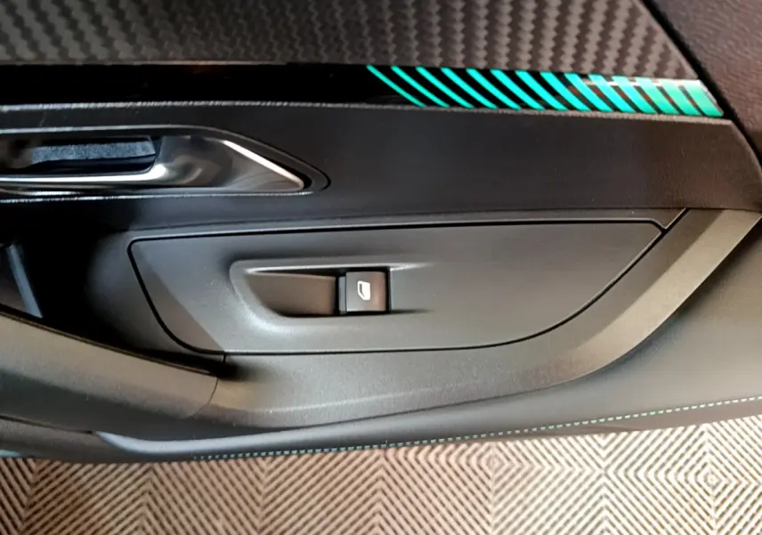 Gros plan sur la commande de lève-vitre côté conducteur avec insert décoratif bleu sur la porte intérieure noire du Peugeot 2008 gris foncé.