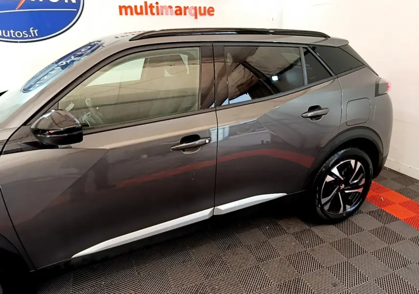 Profil côté gauche du Peugeot 2008 gris foncé 2022 avec jantes noires et toit noir contrasté.