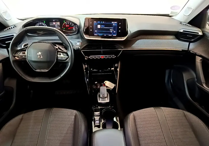 Vue intérieure frontale du tableau de bord et volant cuir noir du Peugeot 2008 gris foncé, avec écran tactile central.