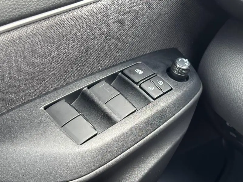 Gros plan sur les commandes de lève-vitres et réglage des rétroviseurs côté conducteur de la Toyota Yaris blanche 2025.