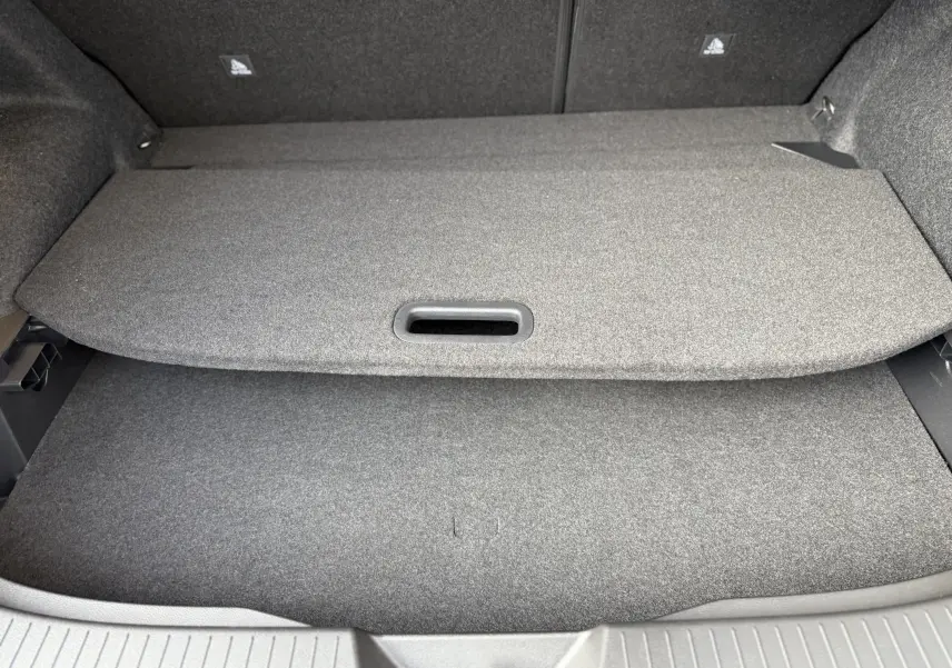 Vue intérieure du coffre du Nissan Qashqai 1.5 E-POWER 2025, avec cache-bagages gris et revêtement tissu.