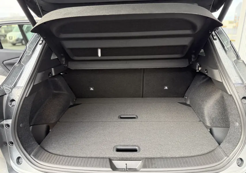 Coffre ouvert vu de l'arrière d'un Nissan Qashqai 1.5 E-POWER gris squale metal, espace de chargement plat et spacieux.