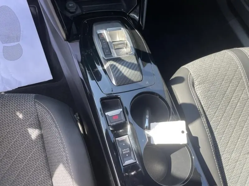 Vue plongeante sur la console centrale noire brillante du Peugeot 2008 gris métal, avec sélecteur de boîte auto et boutons Drive Mode.