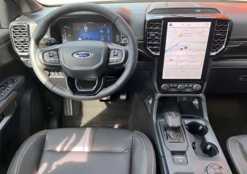 Vue intérieure frontale du Ford Ranger 2026, volant cuir multifonctions, écran tactile vertical et sellerie noire avec surpiqûres.