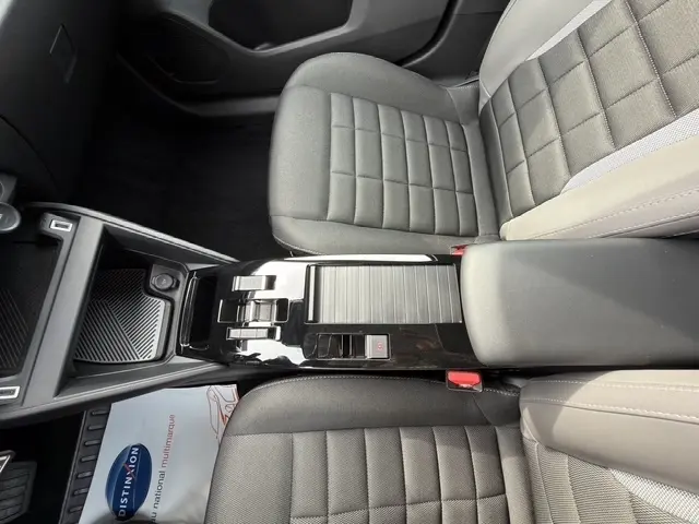 Vue intérieure centrée sur la console centrale noire et les sièges gris du Citroën C4 hybride 2025.
