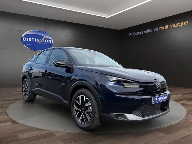Vue 3/4 avant d'une Citroën C4 hybride bleu foncé avec jantes alliage, feux LED et rétroviseurs électriques dans un showroom.