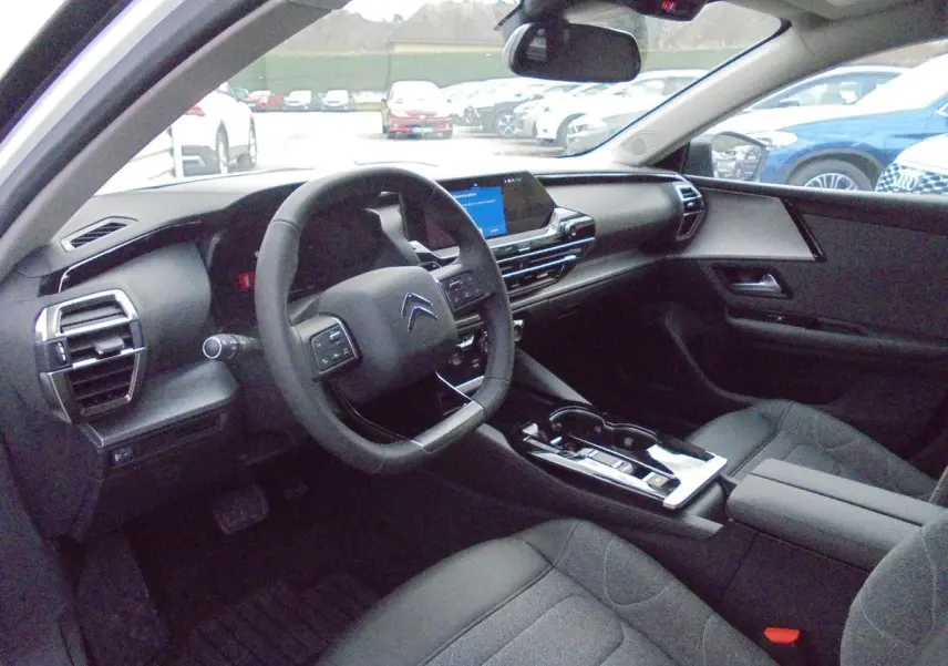 Intérieur du Citroën C5 X 2022 vu côté conducteur, tableau de bord moderne avec écran tactile et volant multifonction noir.