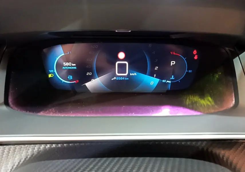 Affichage numérique du tableau de bord de la Peugeot 208 gris foncé, montrant vitesse, autonomie et température moteur.