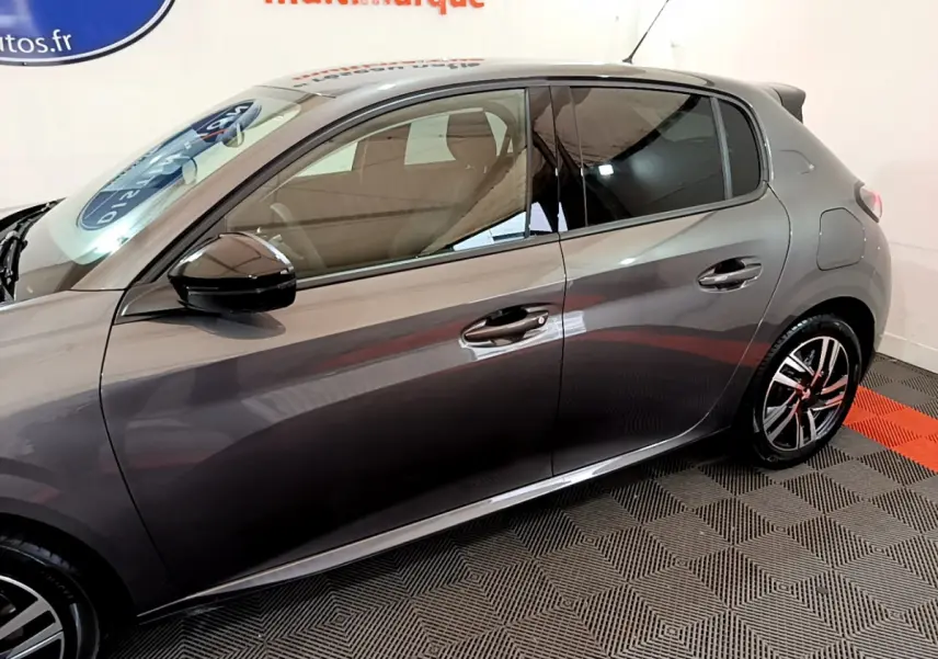 Vue latérale droite d'une Peugeot 208 gris foncé, mettant en valeur les jantes alliage et les rétroviseurs noirs brillants.