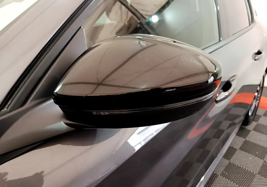 Gros plan sur le rétroviseur noir côté gauche d’une Peugeot 208 gris foncé vue de profil.
