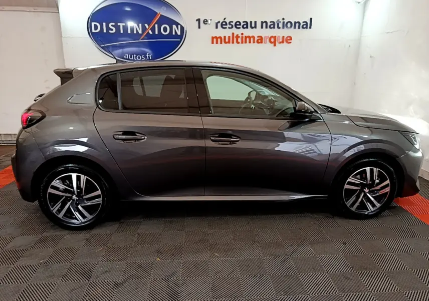 Peugeot 208 gris foncé vue de profil côté gauche, avec jantes alliage et vitres teintées en intérieur showroom.