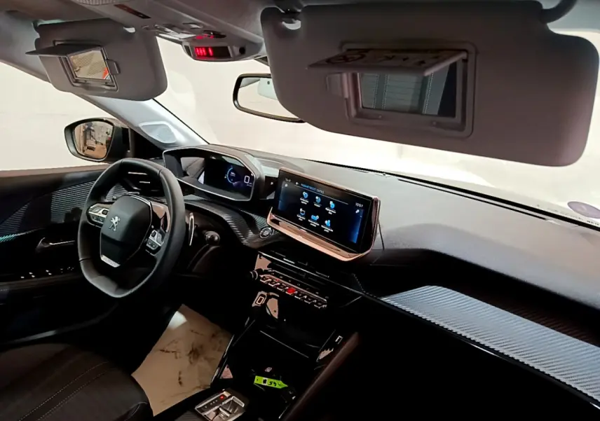 Vue intérieure côté conducteur de la Peugeot 208 gris foncé, avec tableau de bord numérique et écran tactile central.