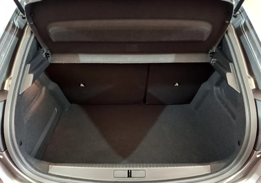Coffre ouvert vu de dessus d'une Peugeot 208 gris foncé, montrant l'espace de rangement intérieur vide.