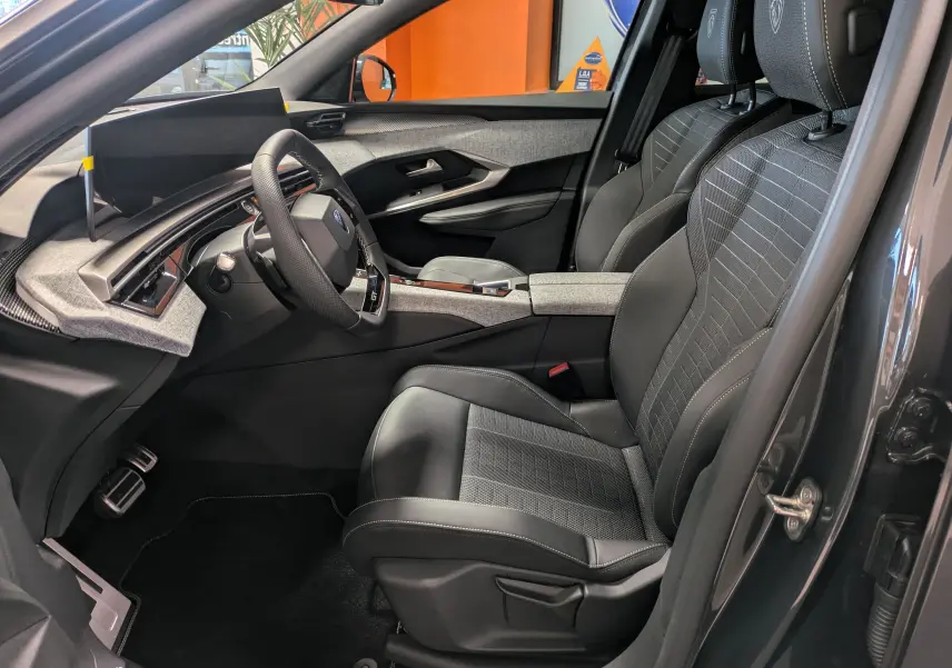 Intérieur côté conducteur du Peugeot 3008 Hybrid gris titane, avec sièges tissu/tepp noir et volant GT visible.
