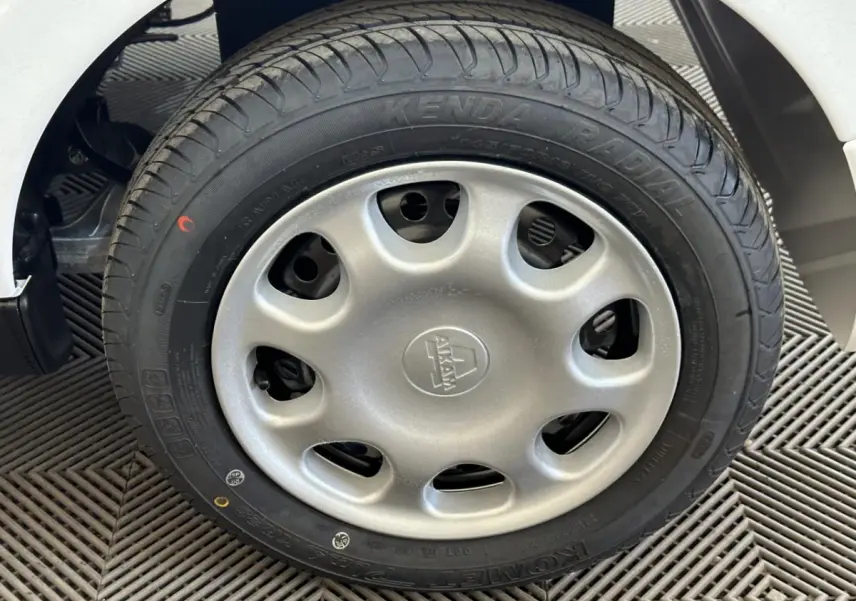 Gros plan sur la roue arrière droite d'une Aixam Minauto E Access blanche 2025 avec pneus neufs et passage de roue visible.