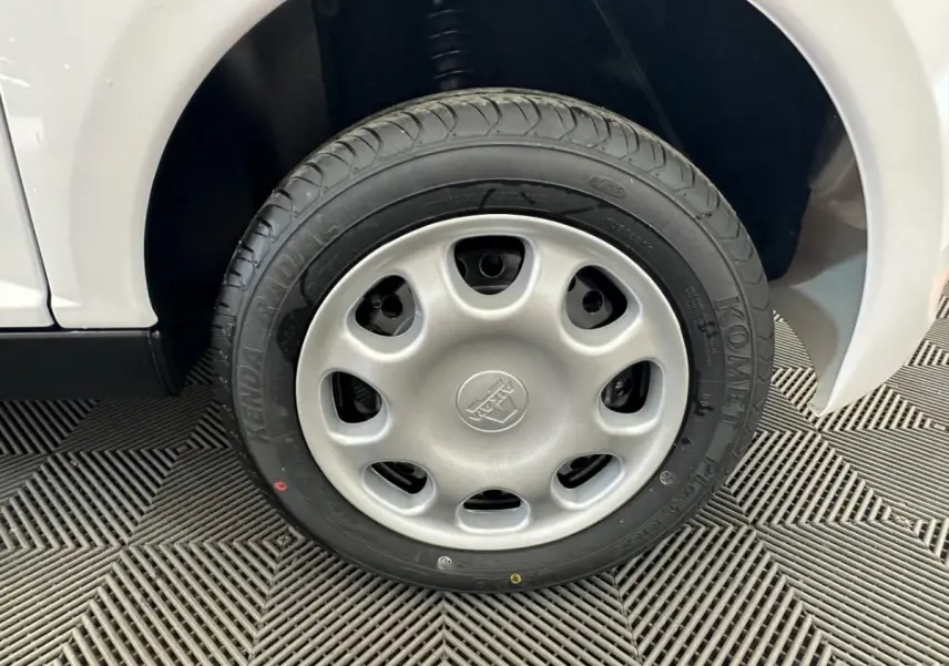 Gros plan sur la roue avant droite d'une Aixam Minauto E Access blanche, montrant le pneu Kenda et l'aile du véhicule.