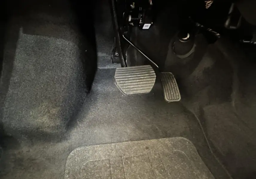 Vue rapprochée des pédales d'accélérateur et de frein sur le côté conducteur de l'AIXAM MINAUTO E ACCESS 2025 blanc électrique.