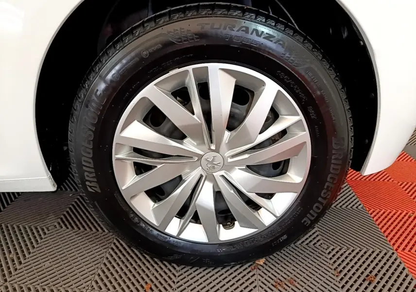 Gros plan sur la roue avant droite d'une Peugeot 208 blanche, avec jante alliage et pneu Bridgestone.