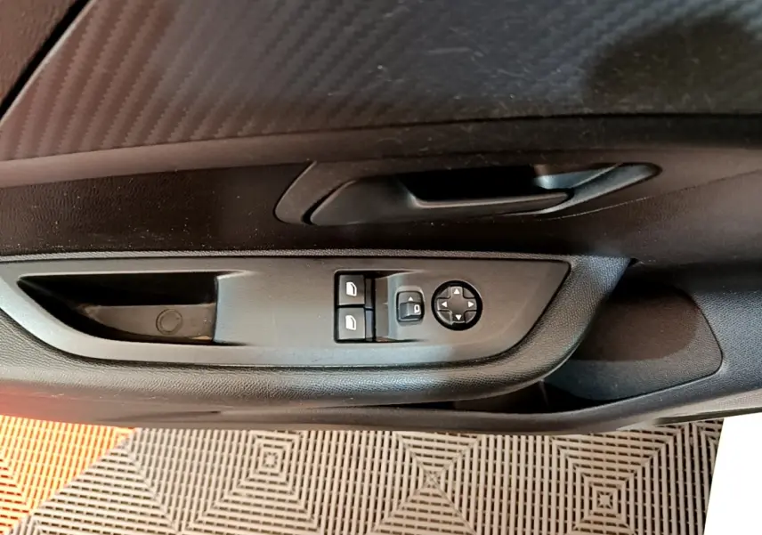 Vue rapprochée de la porte côté conducteur de la Peugeot 208 blanche, montrant les commandes des vitres et rétroviseurs.