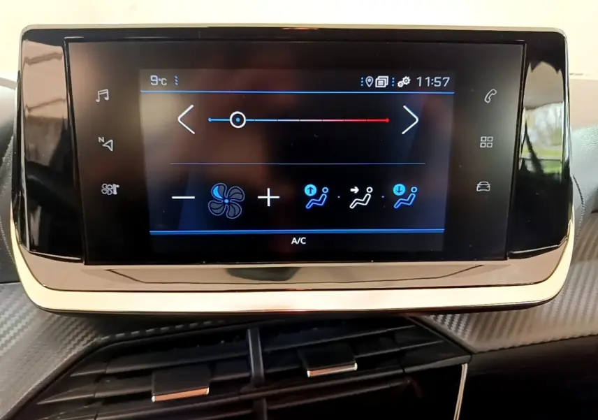 Écran tactile central noir affichant les commandes de climatisation dans l'habitacle d'une Peugeot 208 blanche.