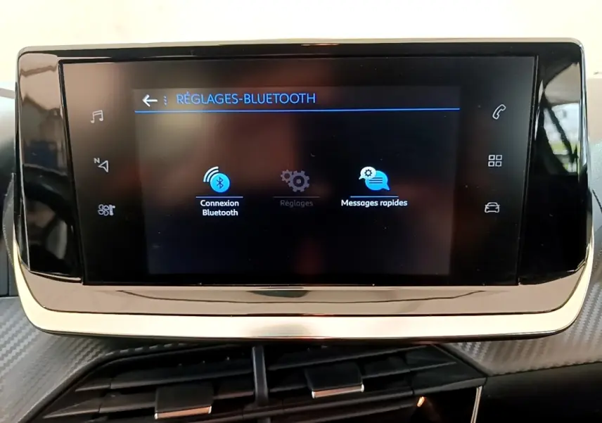 Écran tactile central noir affichant les réglages Bluetooth dans l'habitacle d'une Peugeot 208 blanche.