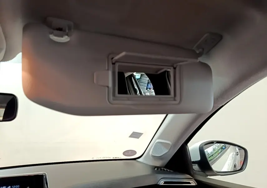 Intérieur de la Peugeot 208 blanc, vue du pare-soleil côté conducteur avec miroir de courtoisie ouvert.