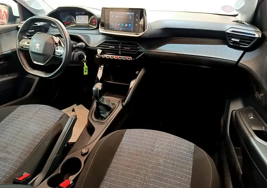 Intérieur de Peugeot 208 2021 vue côté conducteur, tableau de bord avec écran tactile et volant compact noir.