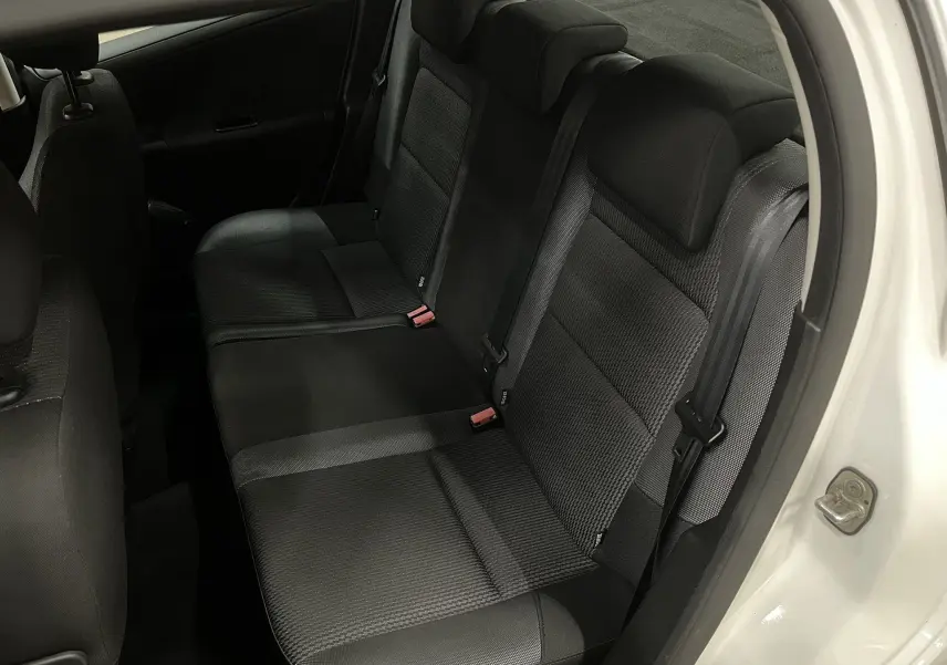 Vue intérieure côté arrière droit montrant la banquette arrière en tissu gris noir d'une Peugeot 207 blanche.