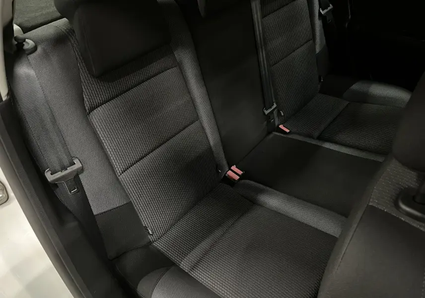 Vue rapprochée de la banquette arrière en tissu gris noir de la Peugeot 207 Active 2011, avec ceintures de sécurité visibles.