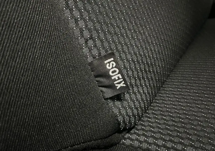 Gros plan sur l’étiquette ISOFIX cousue sur la banquette arrière en tissu gris noir de la Peugeot 207 Active 2011.