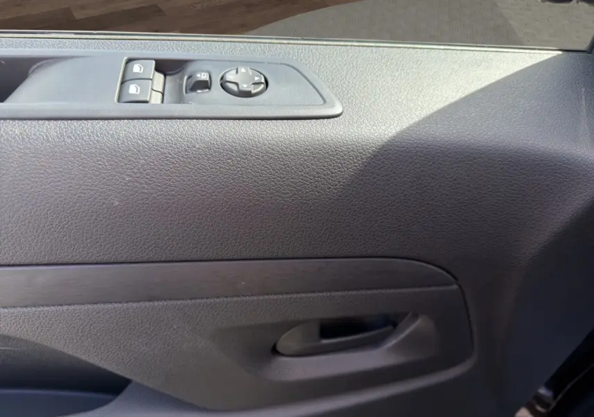 Gros plan sur la porte intérieure côté conducteur du Citroën Jumpy gris foncé avec commandes électriques des vitres et rétroviseurs.