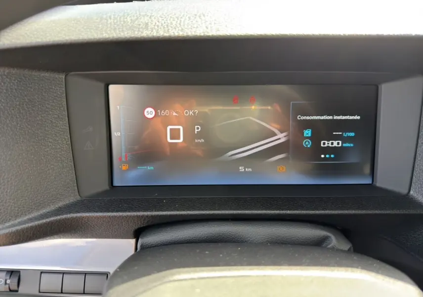 Vue rapprochée du tableau de bord numérique du Citroën Jumpy gris foncé, affichant la consommation instantanée et la vitesse.