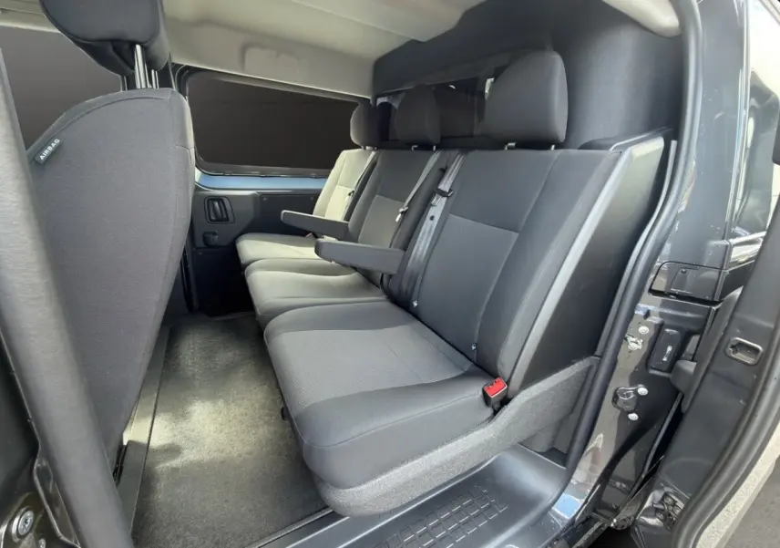 Vue intérieure côté droit sur la banquette arrière grise du Citroën Jumpy 2026 avec cloison vitrée et porte ouverte.