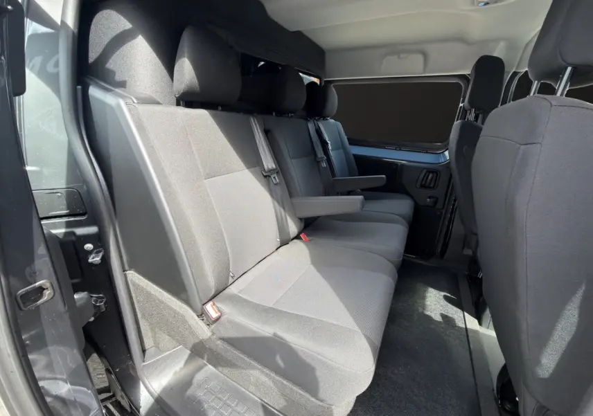 Vue intérieure côté gauche de la banquette arrière grise du Citroën Jumpy 2026 avec accoudoirs et ceintures visibles.