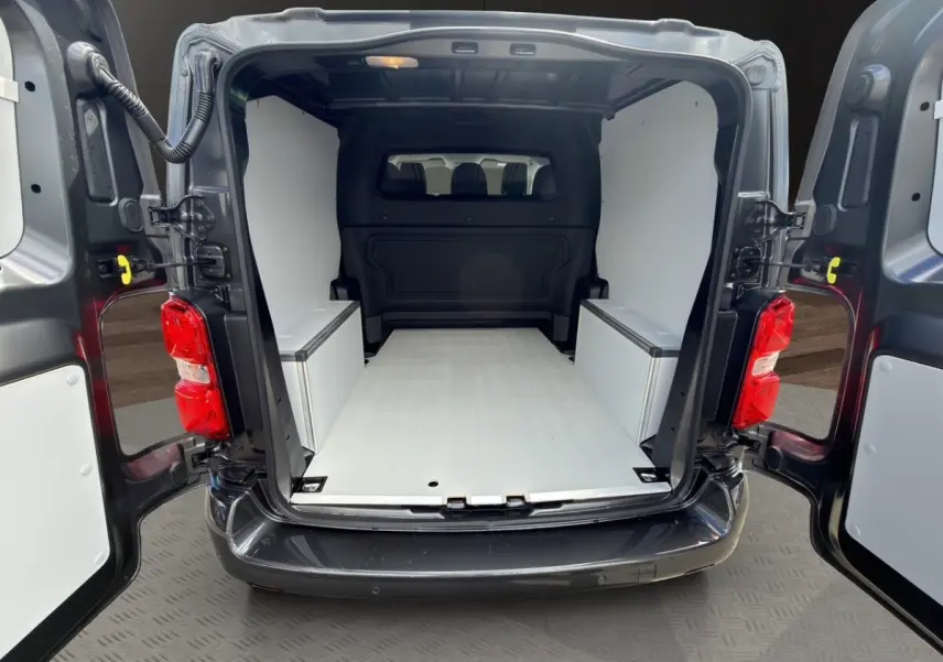 Vue arrière ouverte du Citroën Jumpy gris foncé, montrant l'espace de chargement aménagé avec parois blanches.